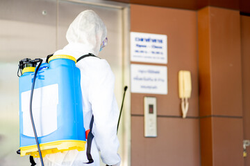 medical health care worker in protective white jumpsuit and pumping spraying machine disinfected virus pandemic in the office building