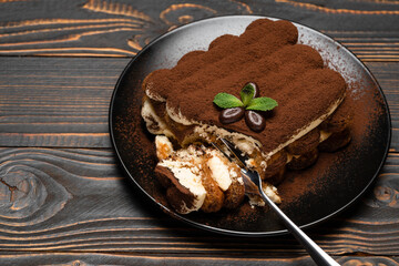 portion of Classic tiramisu dessert on ceramic plate on wooden background