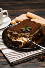 portion of Classic tiramisu dessert and savoiardi cookies on wooden background