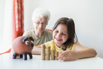 grandmother with her young granddaughter sitting at home with savings