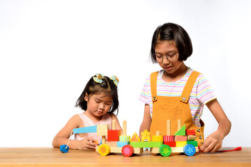 Asian two sisters kids playing together on a wooden table with white background. Skill of children, Childhood roles and Birth order, Child development concept