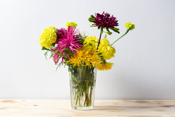 Autumn bright shaggy flowers bouquet in vase on wooden table