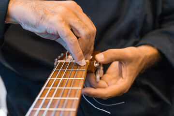 
Male hands changing the strings of a classical guitar
Luthier putting nylon strings on a Spanish...
