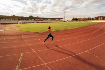 Fototapeta premium Young girl running on running track