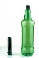PET preforms and a green plastic bottle. Blank for a plastic bottle, on a white background
