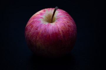 One red fresh apple on a black background. Healthy fruit and breakfast.