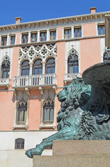 
typical venetian palace with metallic statue of the winged lion in the foreground