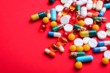 Background of colorful capsules and pills on red background with copy space. Symbol of medicine