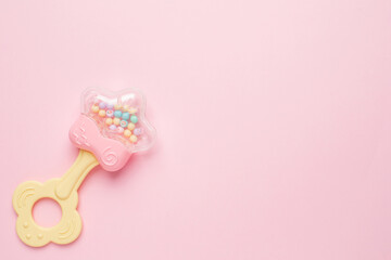 Cute baby rattle with teether on pink background with copyspace