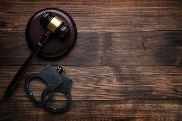 Arrest concept. Handcuffs near judge gavel on dark wooden background
