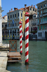 
glimpse of the grand canal in Venice with, in the foreground, two typical poles painted in white and red for mooring boats