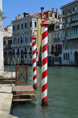
glimpse of the grand canal in Venice with, in the foreground, two typical poles painted in white...
