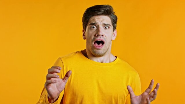 Young scared man shouting loud isolated over yellow background. Stressed and depressed guy trying to get attention. Concept of help and safe