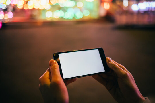 Mobile Phone With Blank Screen In Woman's Hand On Background Festively Lit