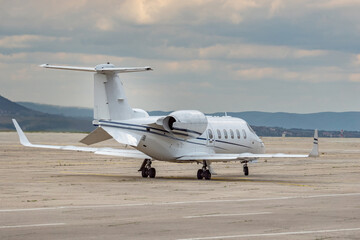 Back side view of white business airplane with two jet engines at airport. Modern technology in fast transportation, business travel and tourism, aviation.