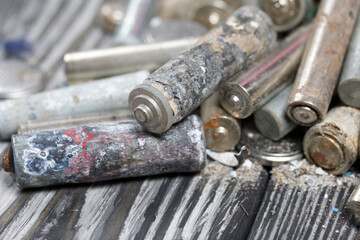Corroded used batteries. On pine boards. Disposal of hazardous waste. Close-up shot.