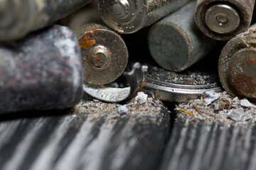 Corroded used batteries. On pine boards. Disposal of hazardous waste. Close-up shot.