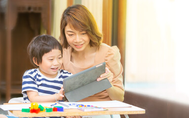 A young boy studies at home with his mom. Home school distance learning and happy learning online education concept