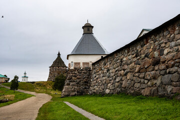 an old stone fortress-monastery with towers and internal buildings against the background of a rainy sky