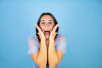 Fototapeta premium Young beautiful woman over isolated blue background screaming and surprised with her hands around her mouth