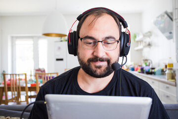 Adult young man in headset speaking by webcam