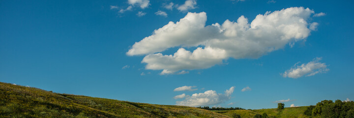 Fototapeta na wymiar Peaks of hills and white clouds against the blue sky. Web banner.