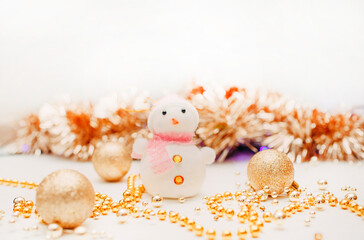 white snowman among gold ornaments as symbol of coming new year