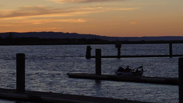 Summer Sunset over Jetty Island, Port Gardner Bay, Everett Washington. Silhouette of rower coming into docks.