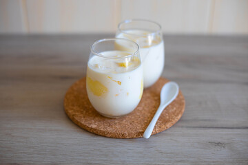 Delicious milk dessert with pieces of melon in glass glasses on wooden table