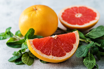 Red grapefruit with slaces and mint leaves on a light background