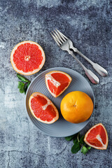 Red grapefruit with slaces and mint leaves on a light background
