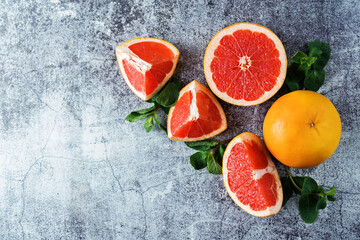 Red grapefruit with slaces and mint leaves on a light background