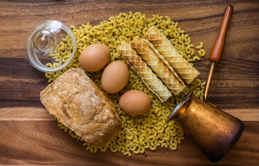 Fototapeta na wymiar Bakery ingredients - bread, eggs, wafer rolls, Cezve, pasta on wood table. Sweet pastry baking concept. Flat lay, copy space, top view.