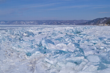 large iridescent crystals white blue ice floes with cracks glow in the light of the sun, lake baikal in snow winter, mountains on the horizon