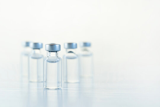 Many transparent vials with vaccine for covid-19 coronavirus, flu, infectious diseases. Injection after clinical trials for vaccination of human, child, adult, senior. Medicine, drug concept