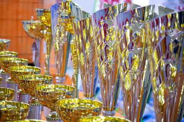 beautiful gold cup on the background of cups for awarding. Prizes for winners, a collection of gold-plated cups for awarding championships
