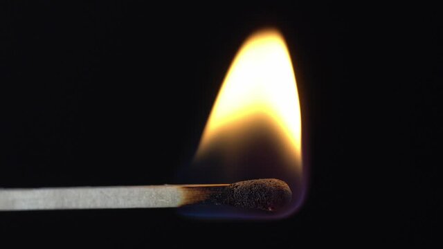 Close-up of burning match on black