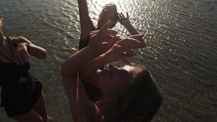 group of young females dancing ecstatic in sea at sunset slow motion
