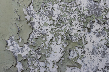 Peeling paint on the wall. Old concrete wall with cracked flaking paint. Weathered rough painted surface with patterns of cracks and peeling. High resolution texture for background and design. Closeup