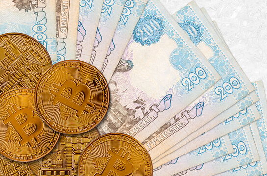 200 Ukrainian hryvnias bills and golden bitcoins. Cryptocurrency investment concept. Crypto mining or trading