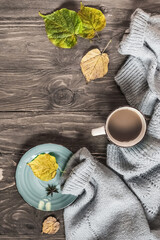 Autumn cozy composition. Cup of coffee, warm sweater, dried leaves on a wooden background. Autumn, fall concept. Flat lay, copy space, 