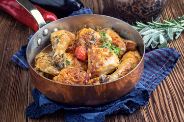 Traditional French coq au vin chicken in sauce offered as close-up in a rustic casserole