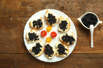 Sandwiches with black caviar on a white plate on the table next to caviar with caviar.