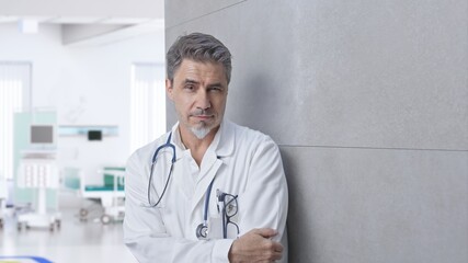 Smiling doctor on hospital corridor, Trustworthy older man with gray hair.