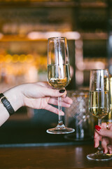 a glass of prosecco in a woman's hand in a bar, making a toast