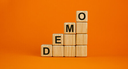 Wood cubes with word 'demo' stacking as step stair on beautiful orange background, copy space....