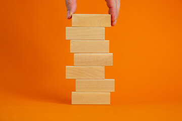 Concept of building success foundation. Men hand put wooden blocks on the stack of wooden blocks....