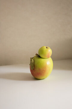 Trendy ugly food.Two Siamese apples joined together on a white table.Funny, unnormal fruit or food waste concept.