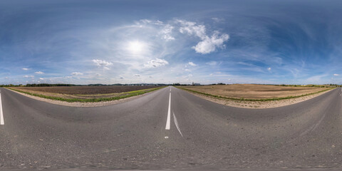 Full spherical seamless panorama 360 degrees angle view on no traffic old asphalt road among fields with clear sky and white clouds in equirectangular projection, VR AR content