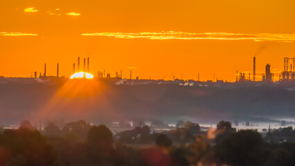 Scarlet sunrise over a chemical plant with pipes